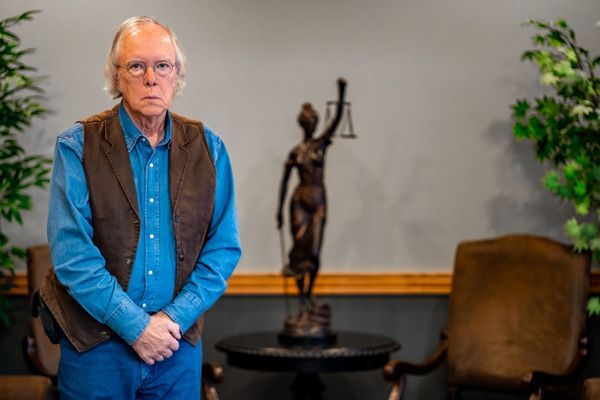 Kenneth Wasserman posing in front of a small bronze statue of Lady Justice