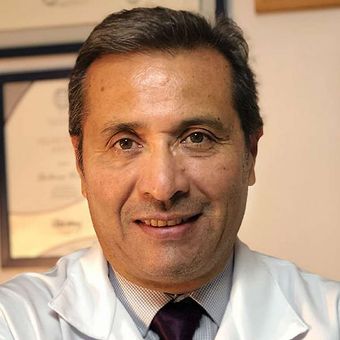 A man in a white coat and tie smiles for the camera