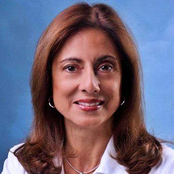 A woman with long brown hair and a white shirt is smiling for the camera.