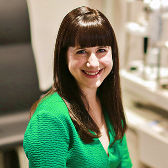 A woman in a green sweater smiles for the camera