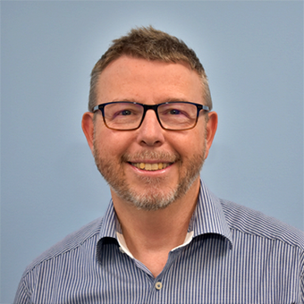 A man with glasses and a beard is smiling for the camera
