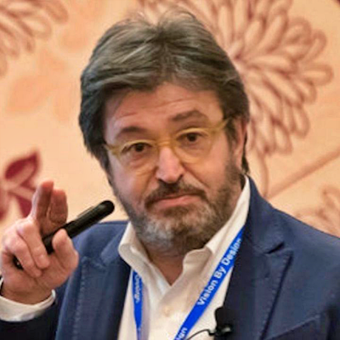 A man with a beard and glasses is holding a microphone in his hand.