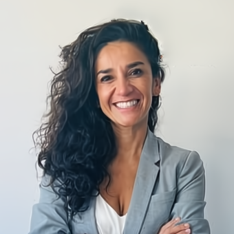 A woman with long dark hair is smiling with her arms crossed.