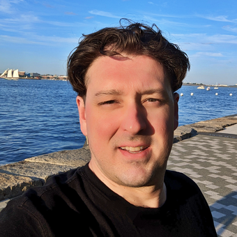 A man wearing a black shirt is smiling for the camera