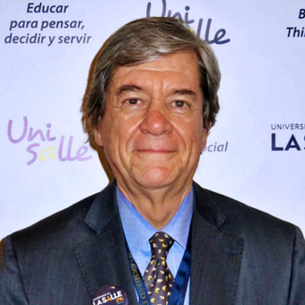 A man in a suit and tie stands in front of a sign that says educar para pensar decidir y servir