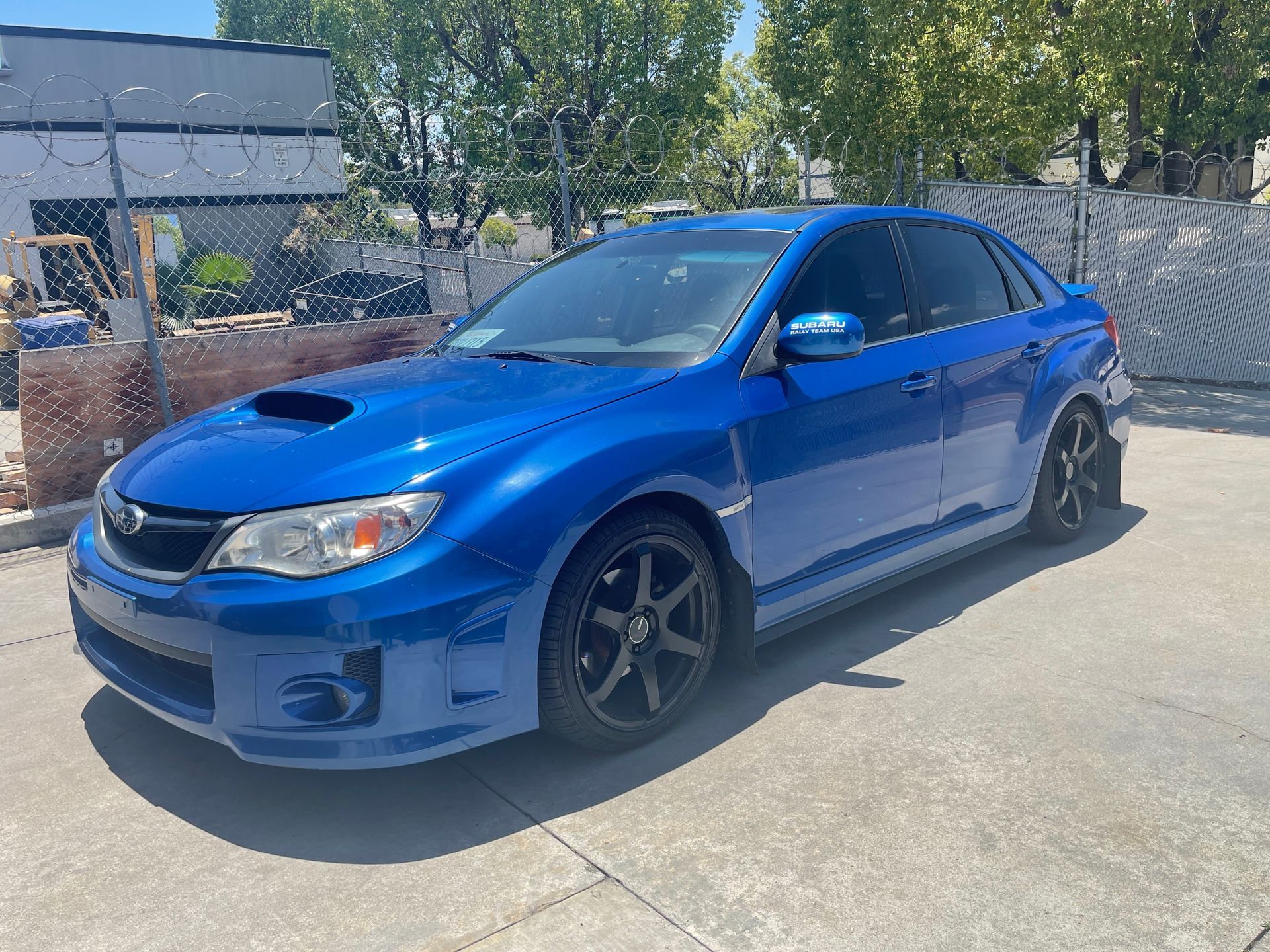 A blue subaru wrx sti is parked in a parking lot.
