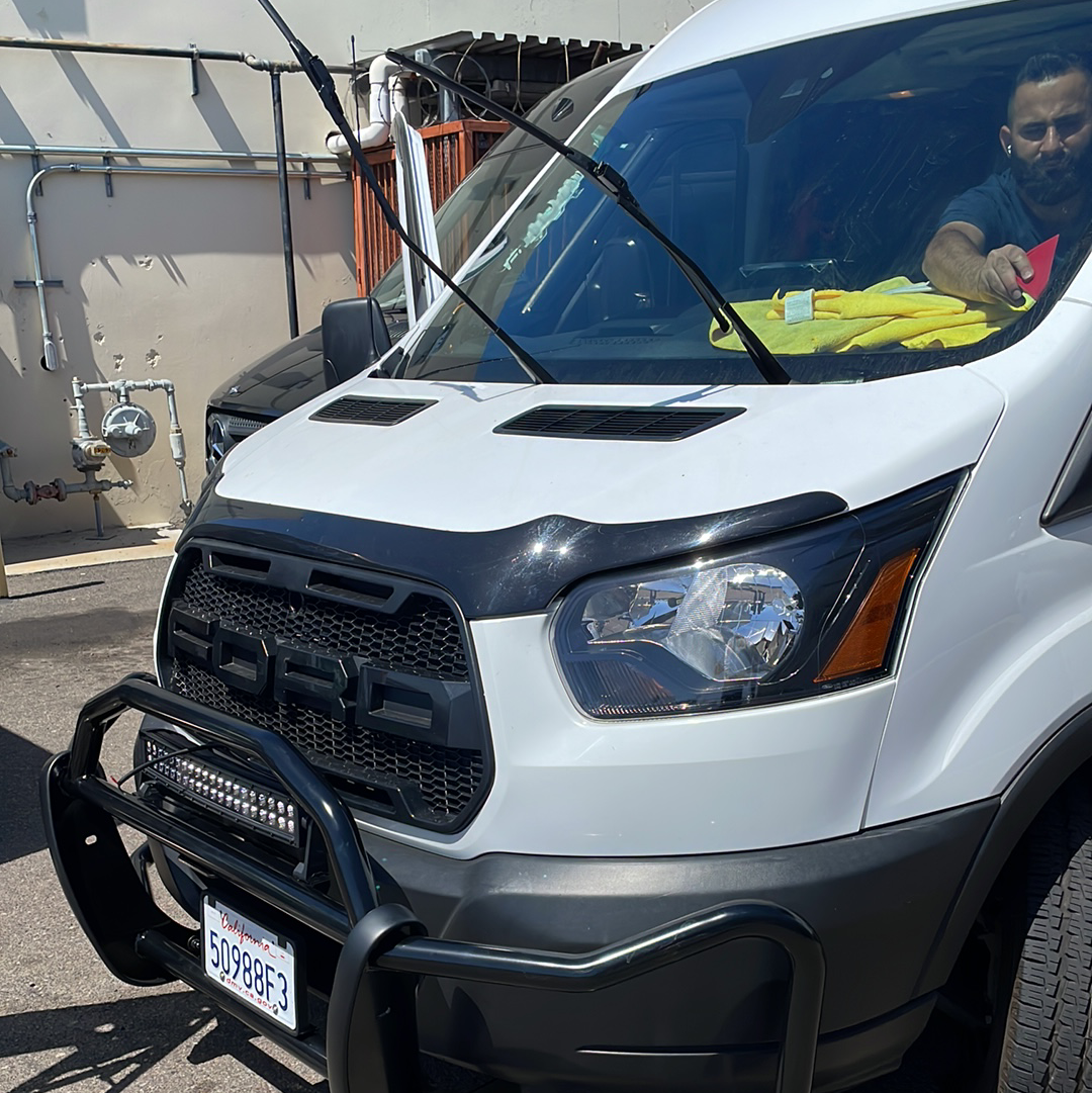 A man is driving a white van with a black bumper