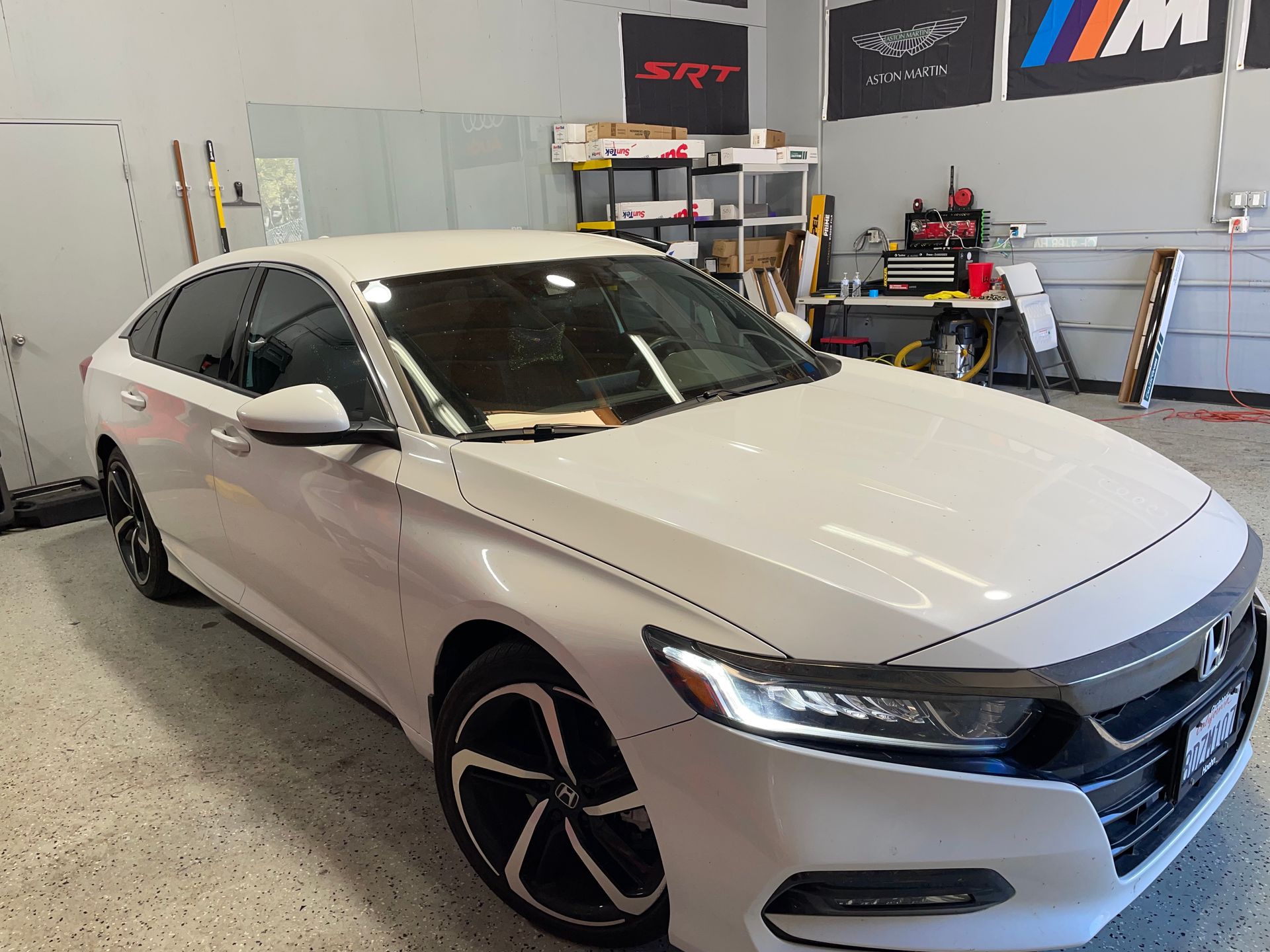 A white honda accord is parked in a garage.