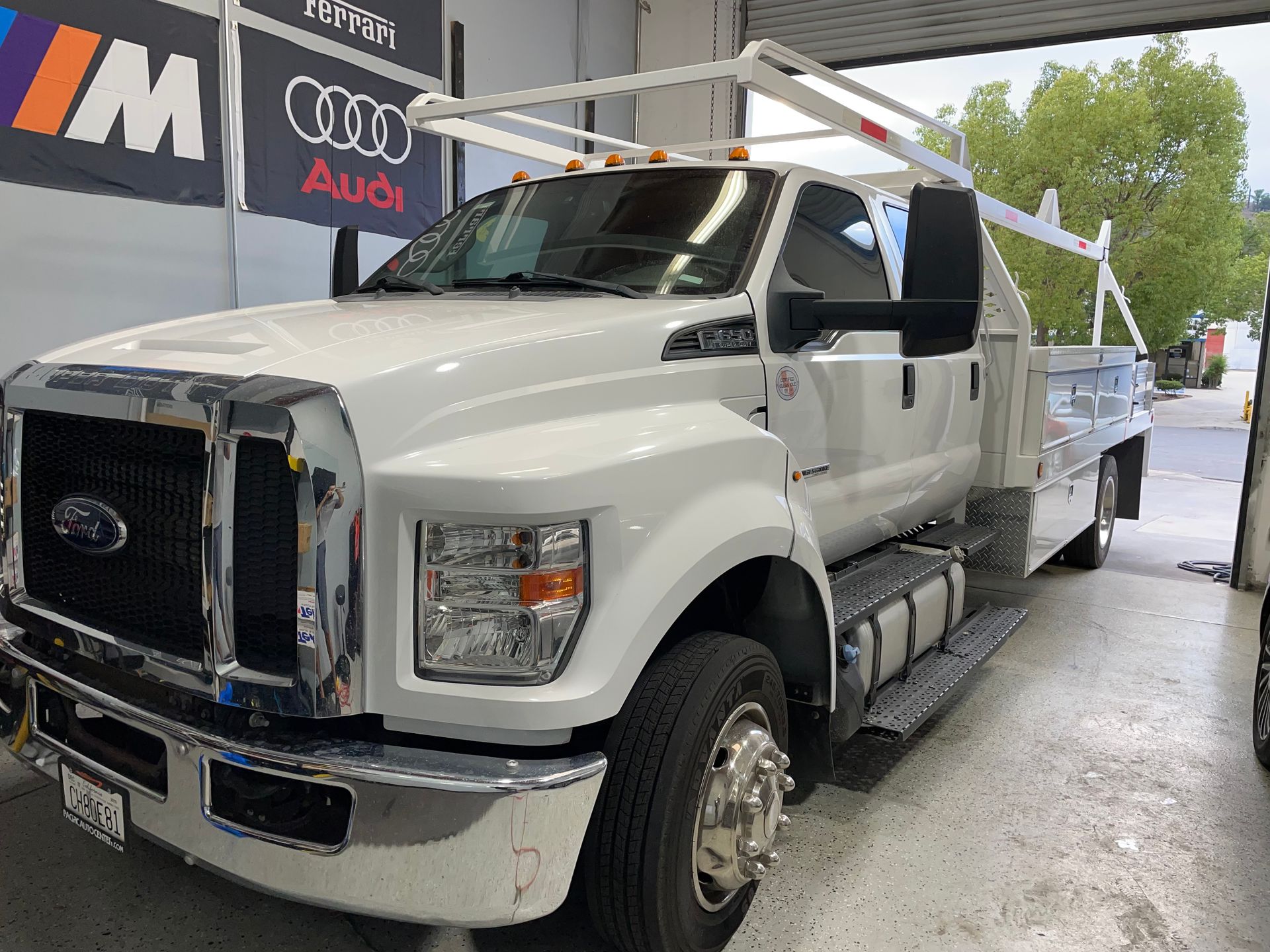 A white truck is parked in a garage next to a sign that says audi.