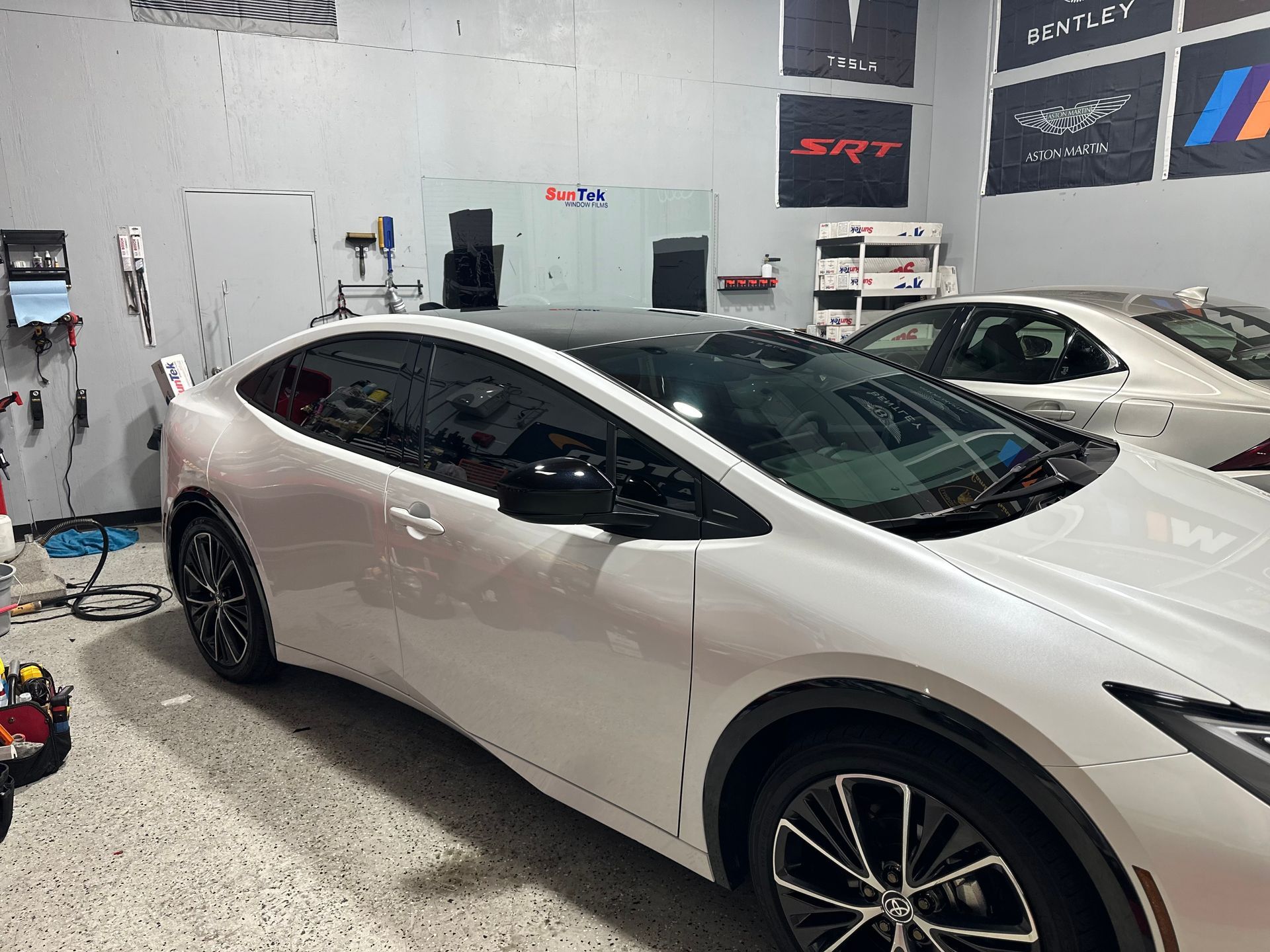 A white car is parked in a garage with other cars.