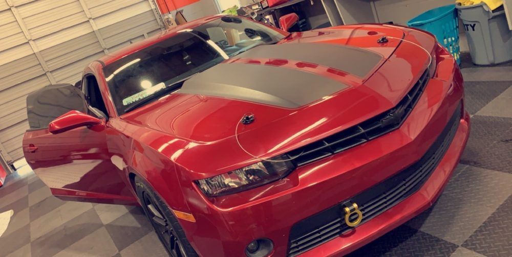 A red car is parked in a garage with the door open.