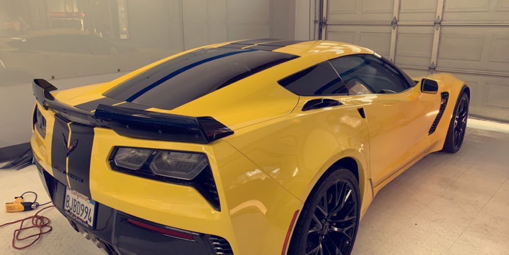 A yellow sports car with black stripes is parked in a garage.