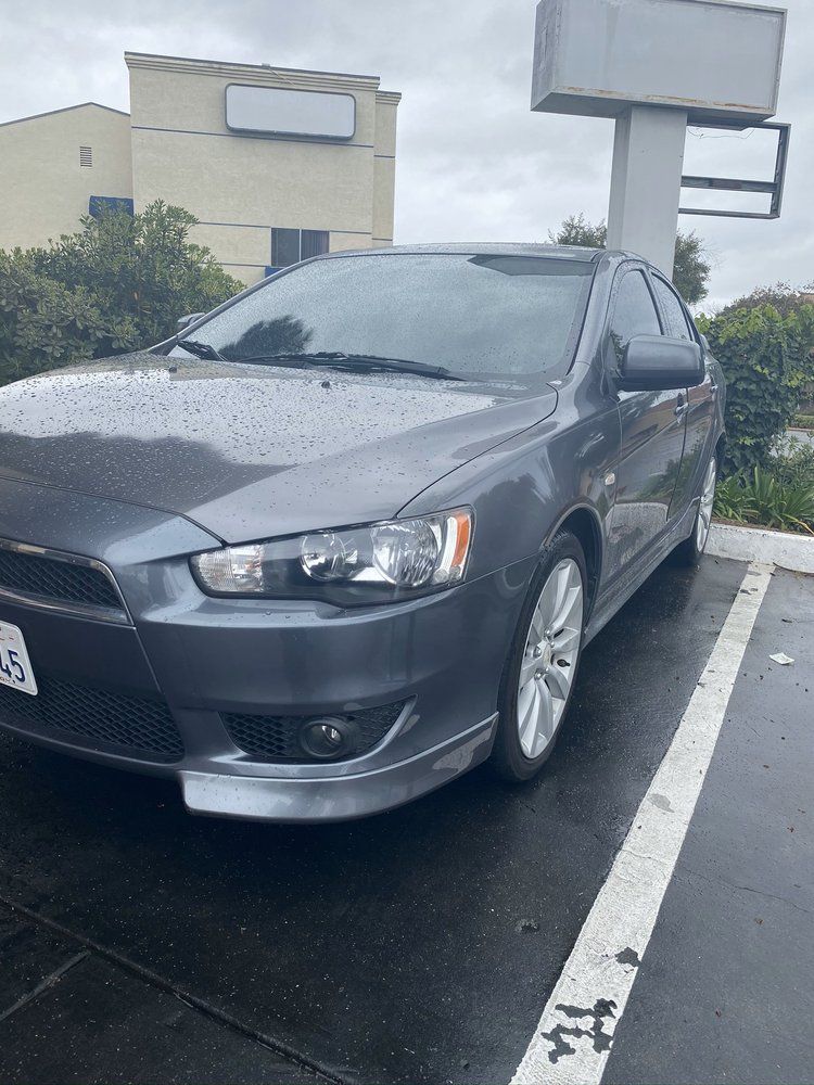 A gray car is parked in a parking lot in front of a building.