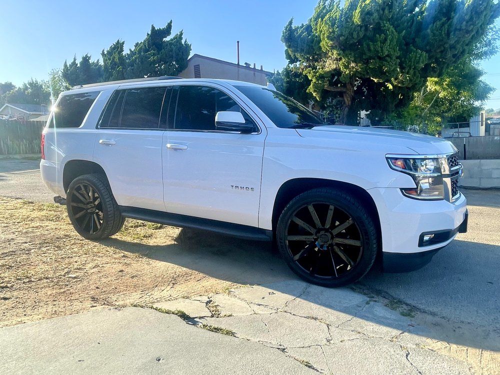 A white suv with black wheels is parked on the side of the road.