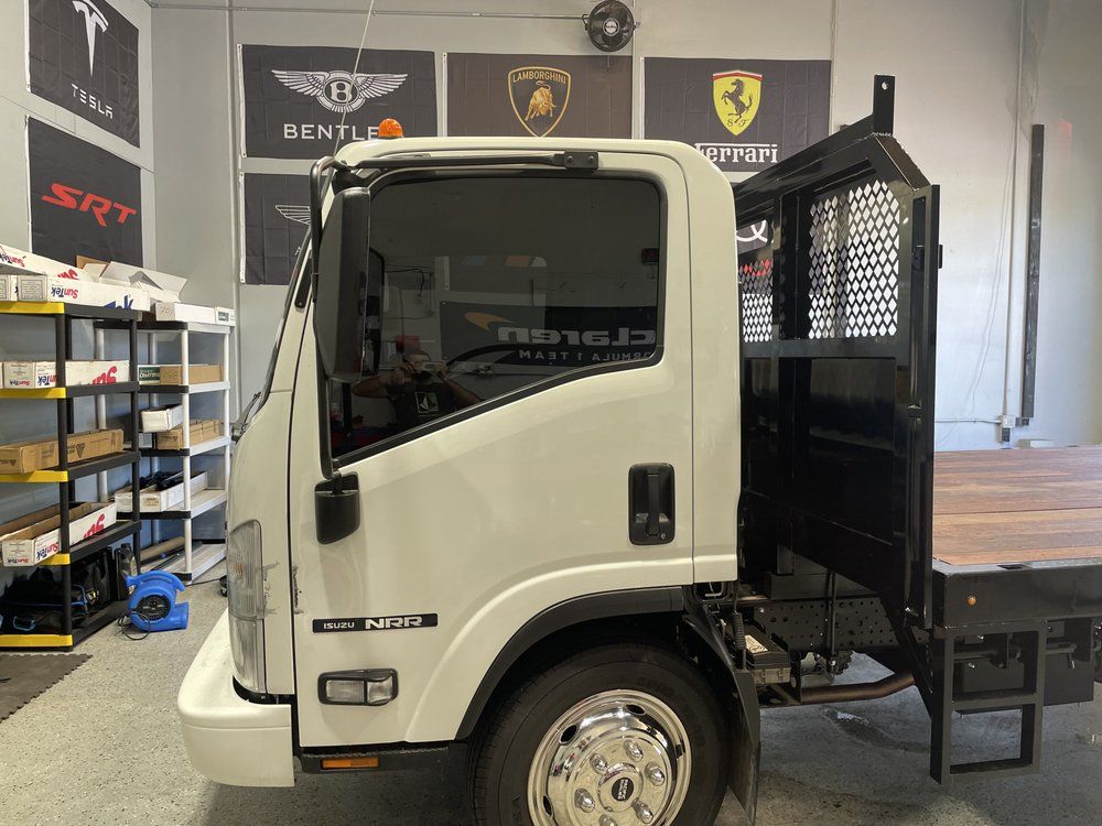A white truck with a wooden bed is parked in a garage.