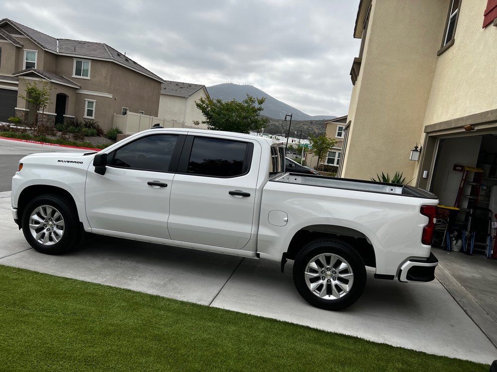 A white truck is parked in a driveway in front of a house.