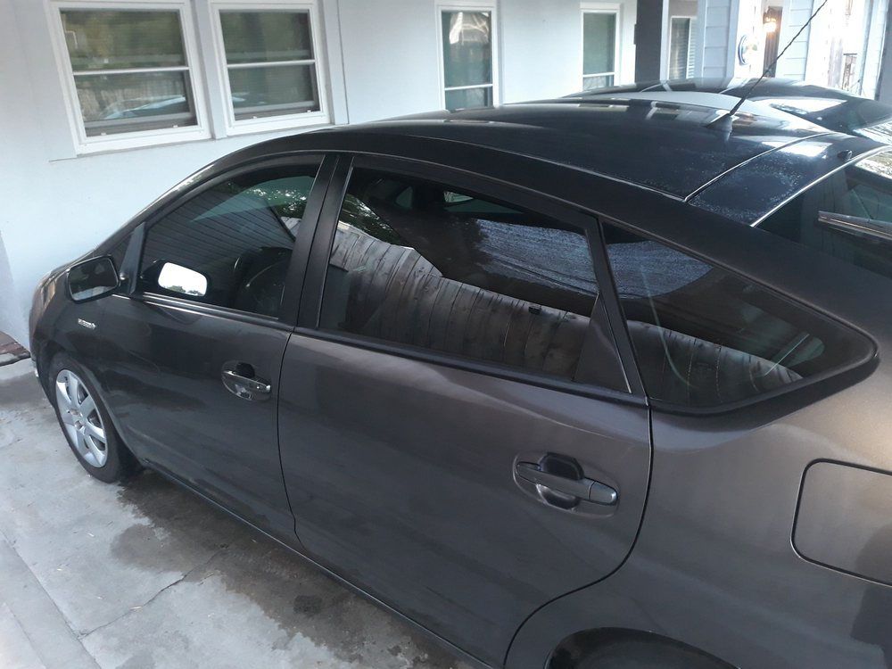 A black car is parked in front of a white house
