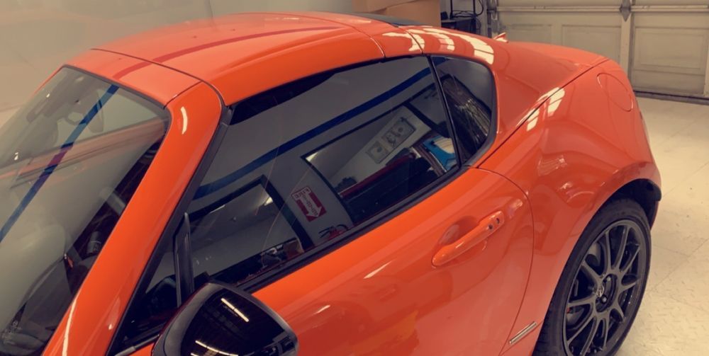 A red sports car is parked in a garage next to a garage door.