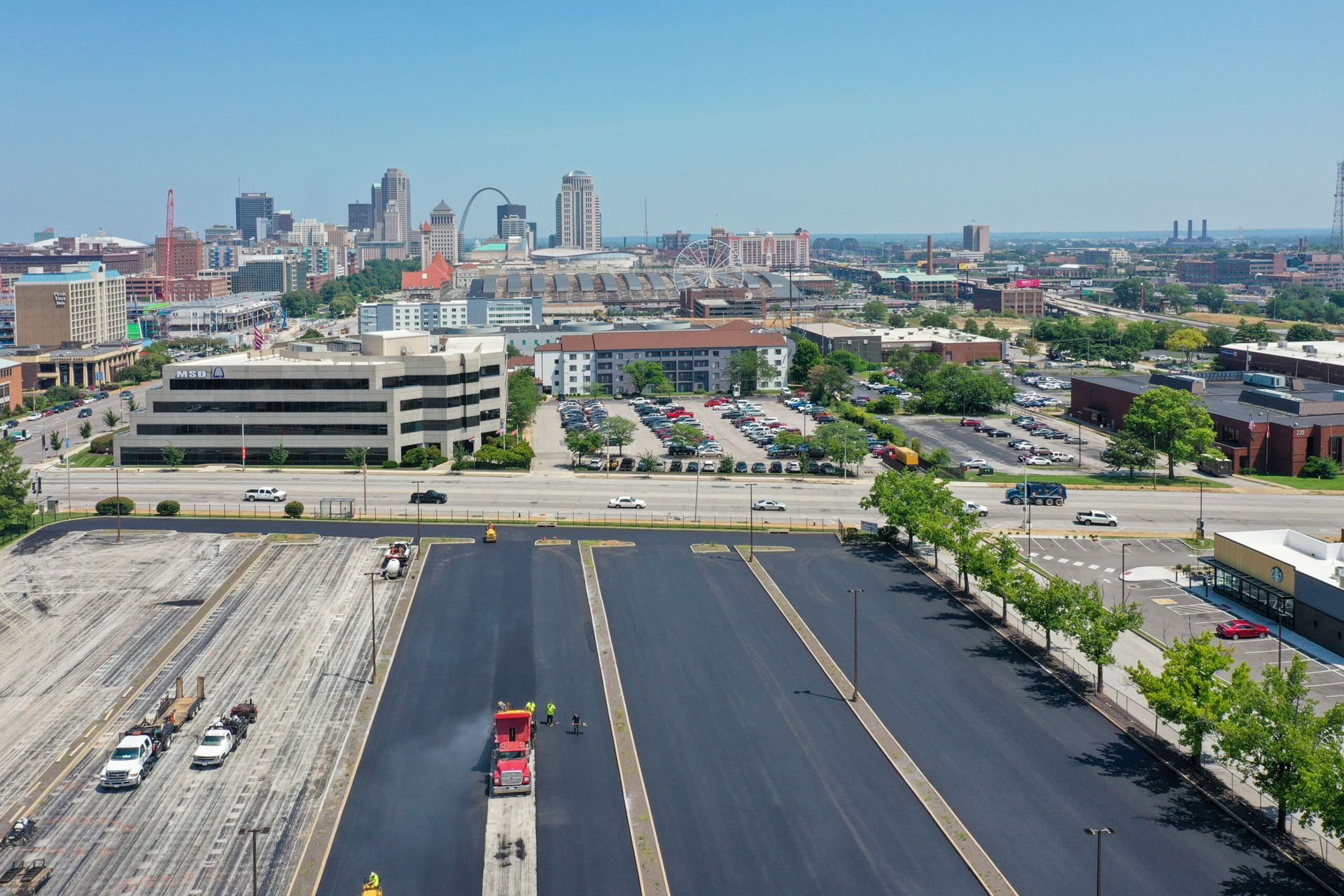 Aerial view of a city skyline beyond a large parking lot and freeway on a clear day