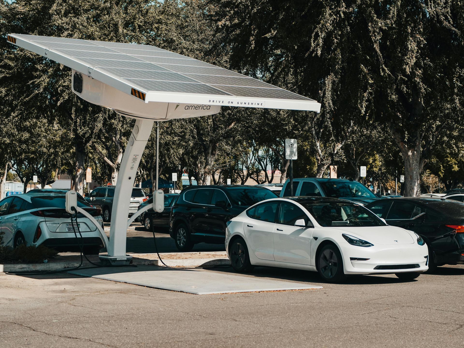 A tesla model 3 is being charged at a solar powered charging station.