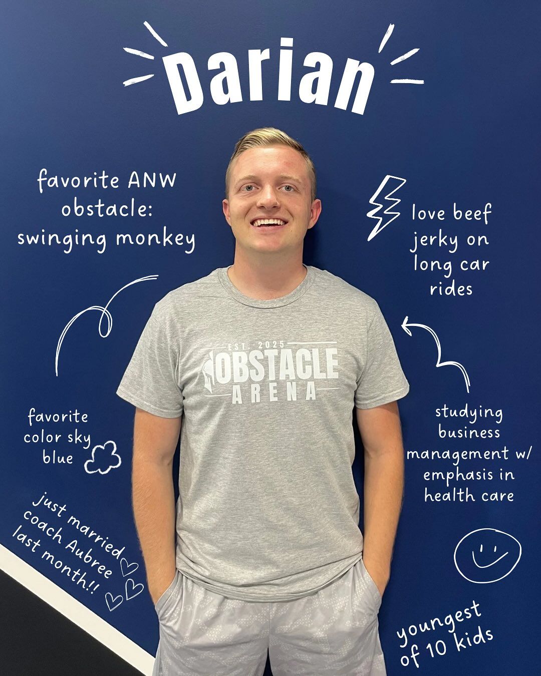 Man named Darian in front of blue wall with facts about him written on it. He is smiling.