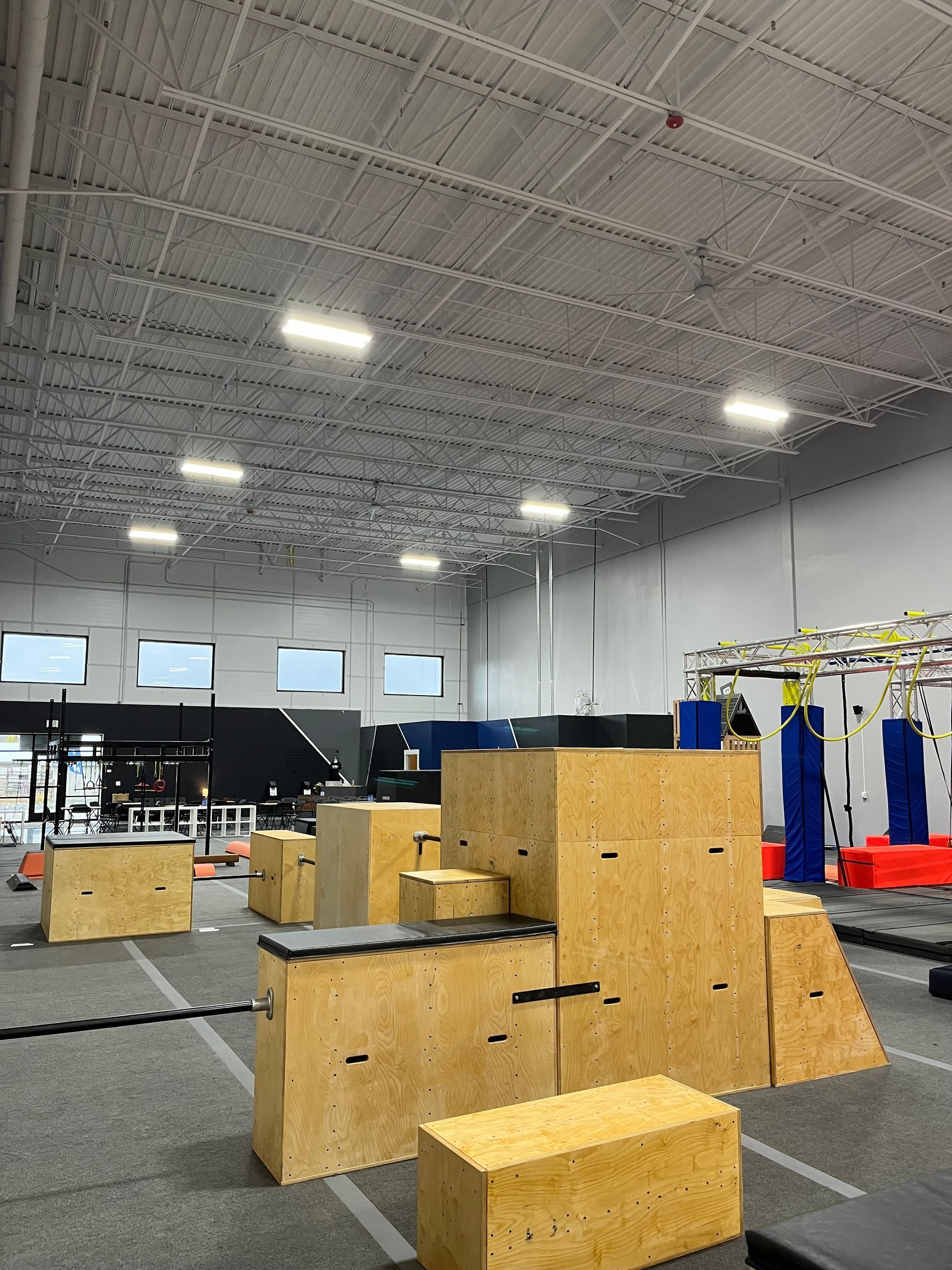 Indoor parkour gym with wooden obstacles and padded floor.