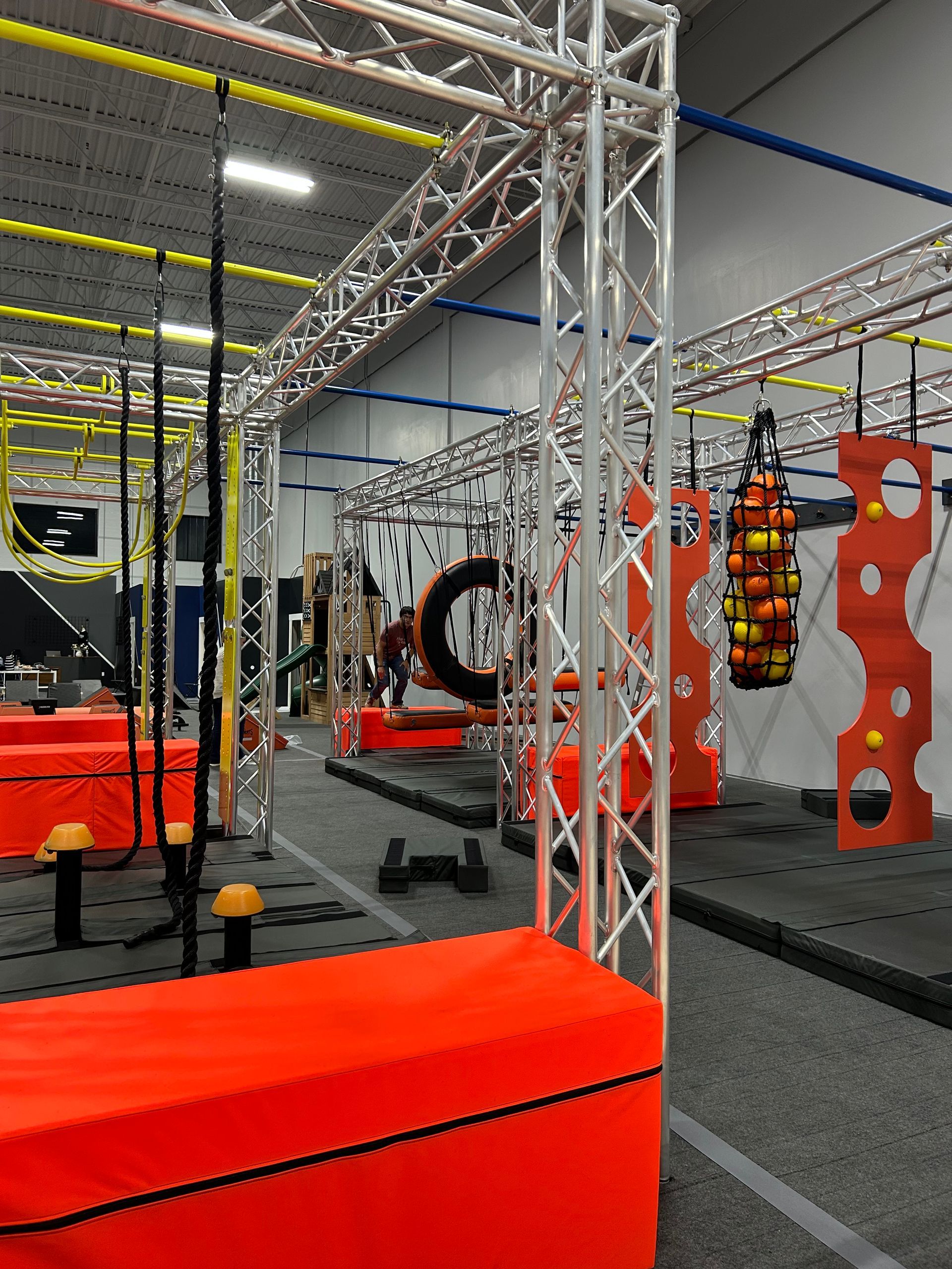 Indoor obstacle course with orange blocks, metal structures, and various challenges.