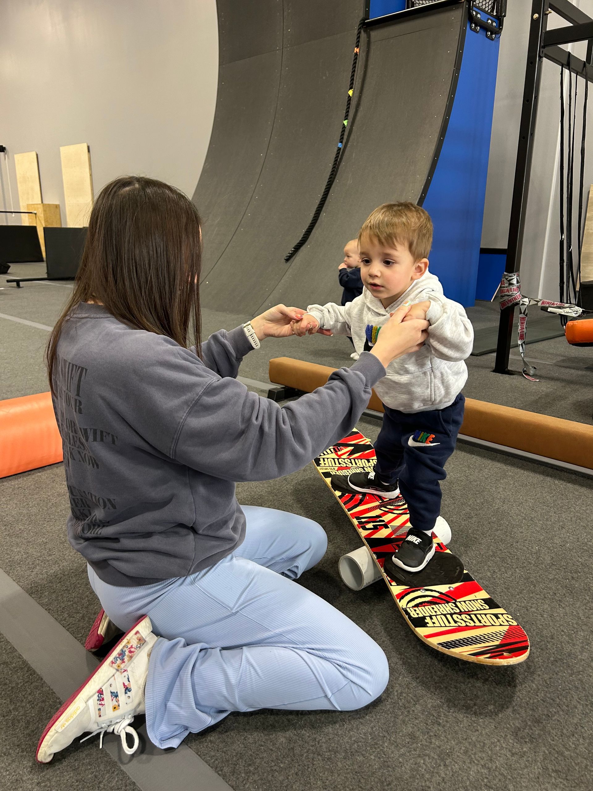 Adult kneeling to help a child balance on a balance board