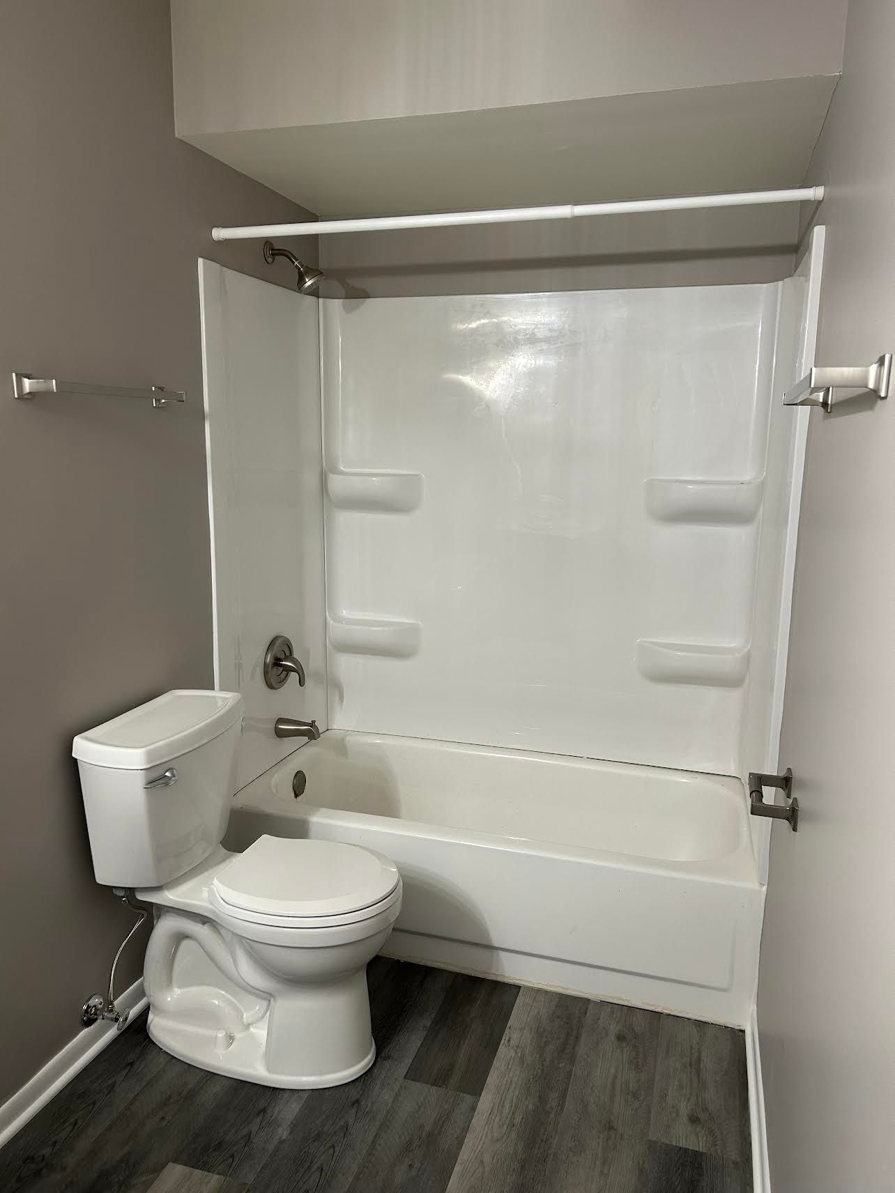 A bathroom with a toilet , bathtub and shower.