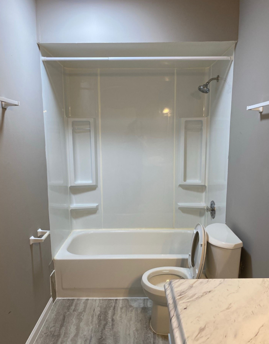 A bathroom with a bathtub , toilet and shower.