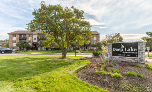 A sign for deep lake apartments is in front of a building.