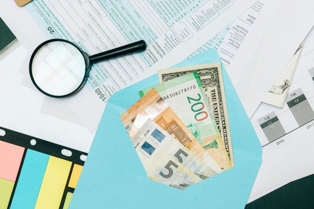 Magnifying glass over documents and a blue envelope with money.