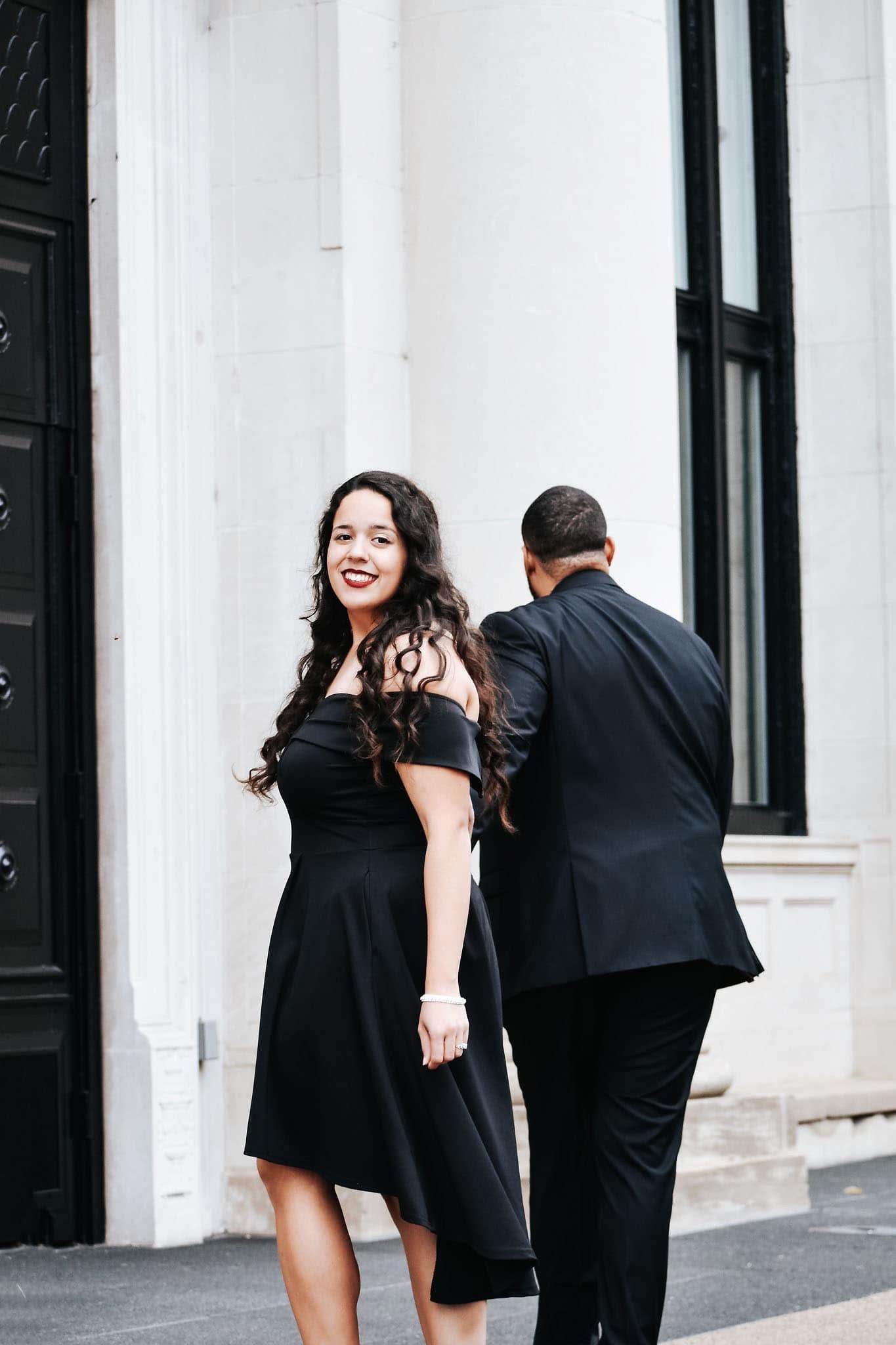 A woman in a black dress is standing next to a man in a black suit.