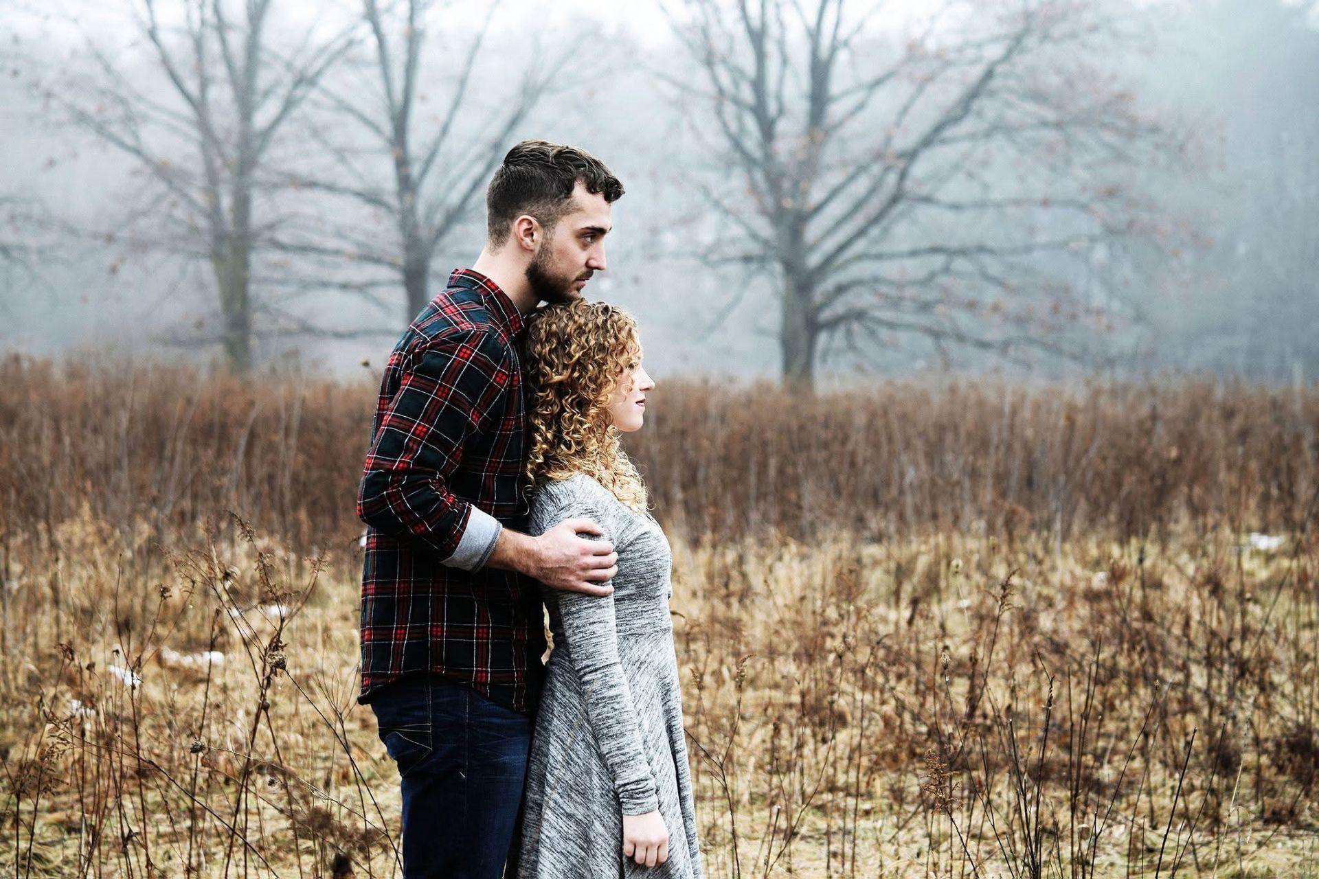 A man and a woman are standing in a field looking at each other.