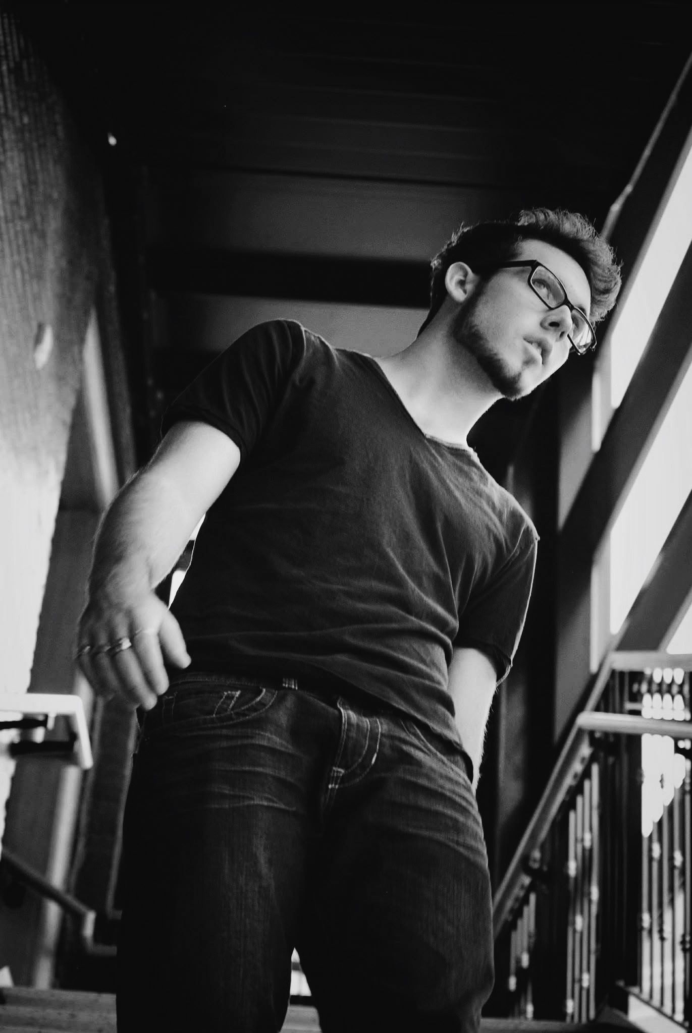 A man wearing glasses and a black shirt is standing on a set of stairs.