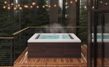 Outdoor hot tub on a wooden deck with string lights and forest view