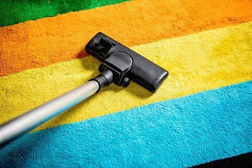 A vacuum cleaner is cleaning a colorful carpet.