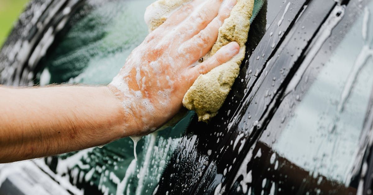 A person is washing a car with a sponge.