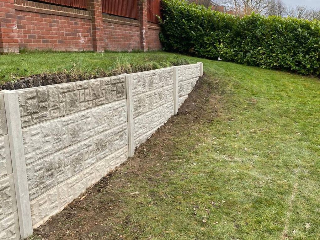 A retaining boundary built from stacked rock-faced concrete gravel boards down a sloping lawn in Ilkeston