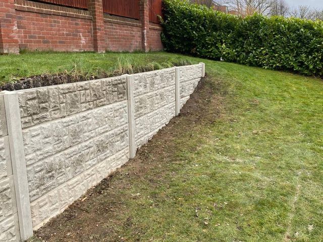 A long run of stacked concrete gravel boards retaining the higher side of a sloping garden in Ilkeston