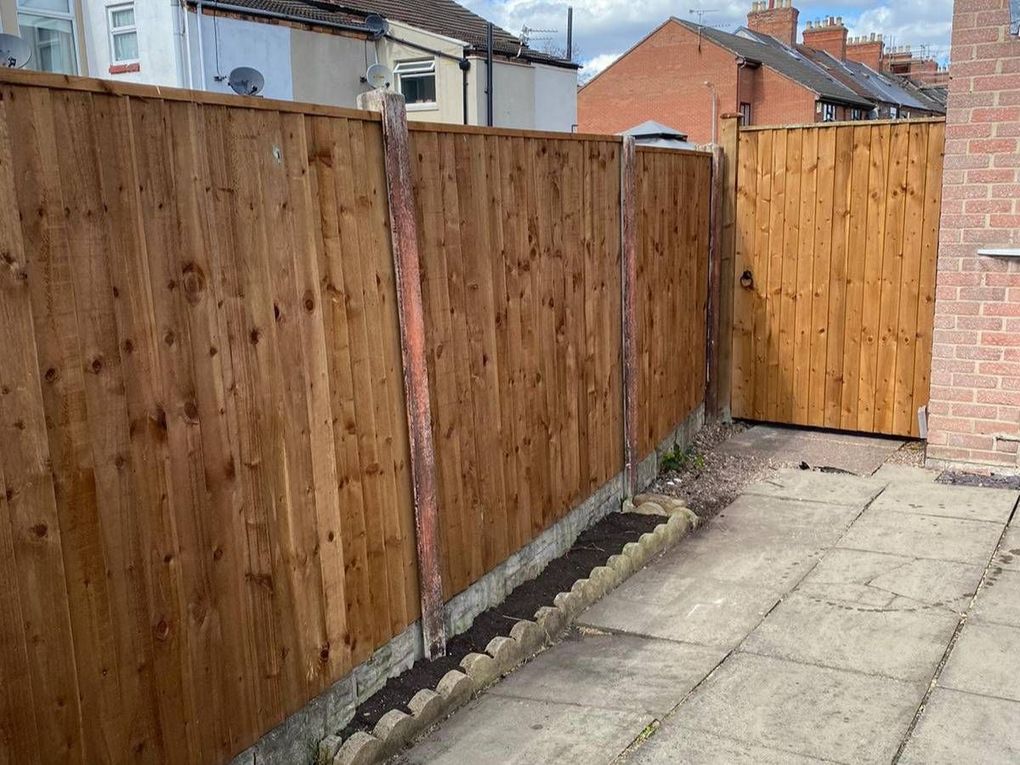 A new closeboard fence on concrete posts alongside a paved side passage in Netherfield