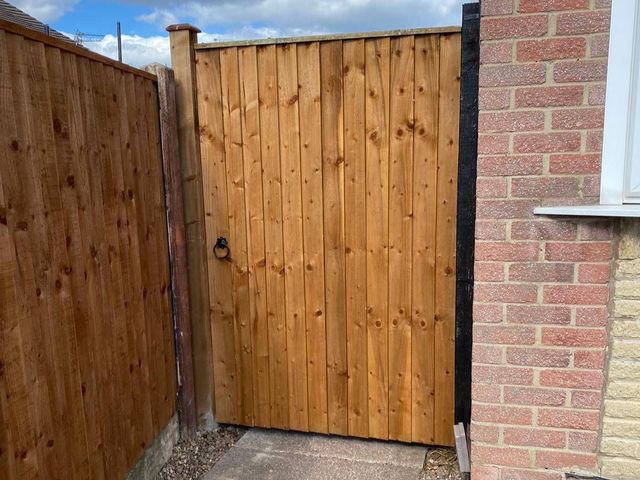 A new braced and ledged timber side gate hung between a brick pier and a rendered wall in Netherfield