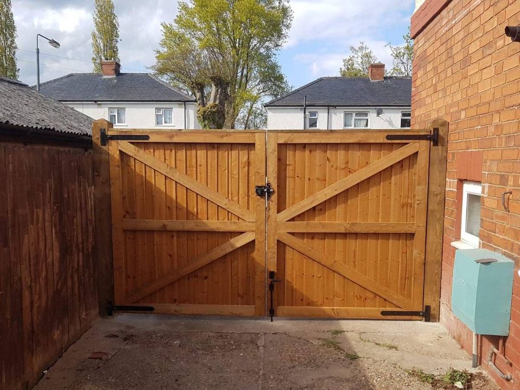 New braced timber double driveway gates fitted between a house wall and brick pier in Kimberley