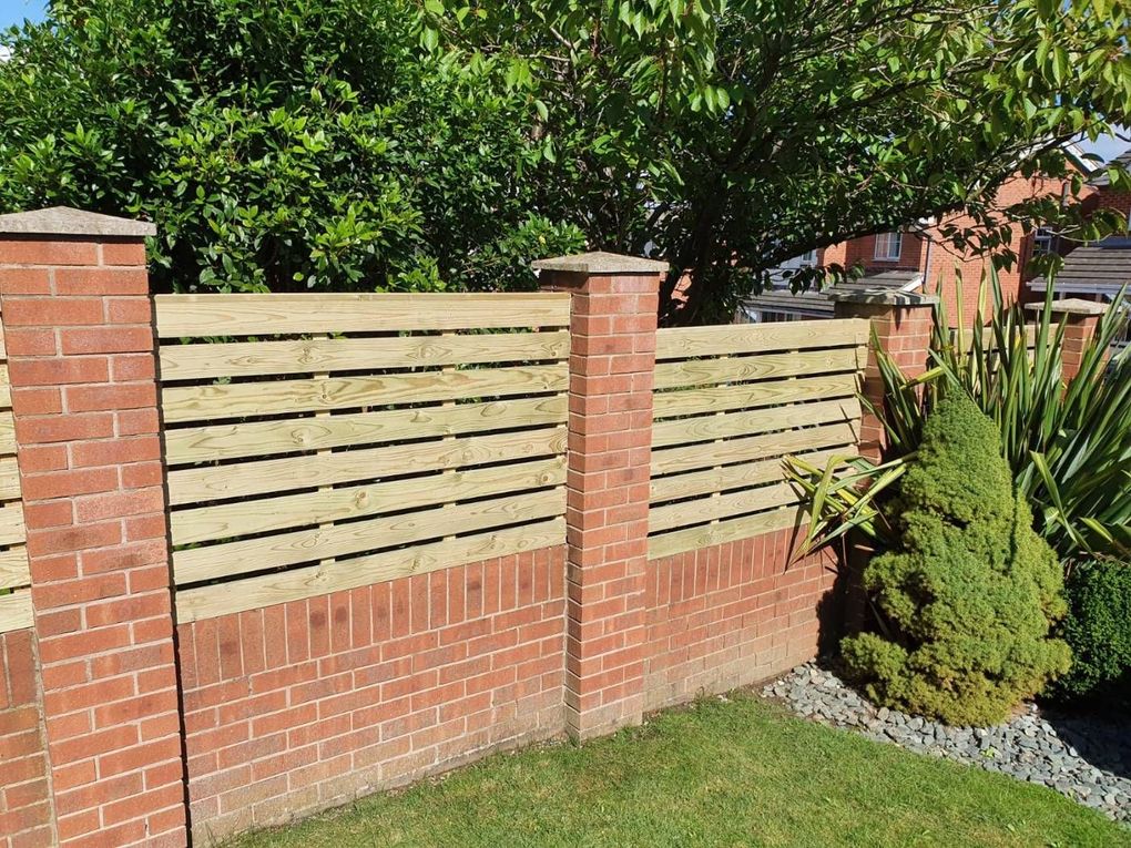 Horizontal slatted timber fence panels fitted on a brick dwarf wall between brick piers in Arnold, Nottingham