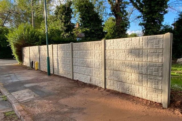 Completed rock-faced concrete post and panel fence along a roadside boundary in Aspley, Nottingham