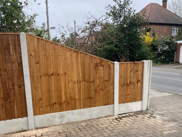 A tall closeboard fence stepped down along a pavement boundary in Stapleford with block paving in front