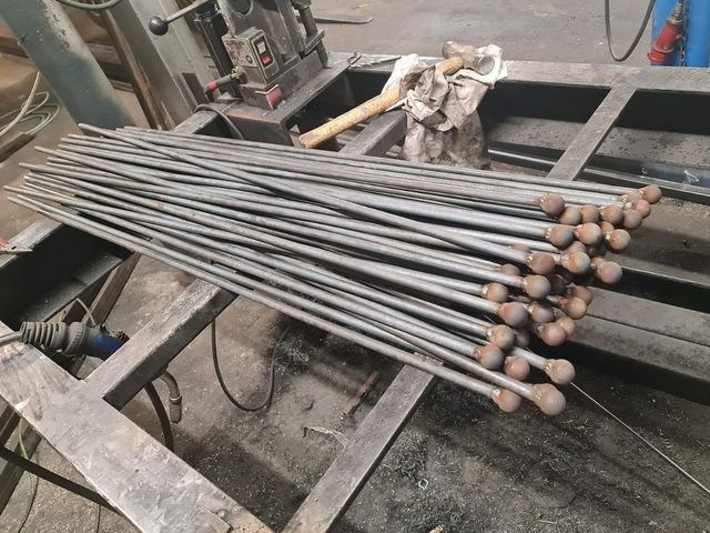 Metal bars with ball tops being individually attached in the workshop