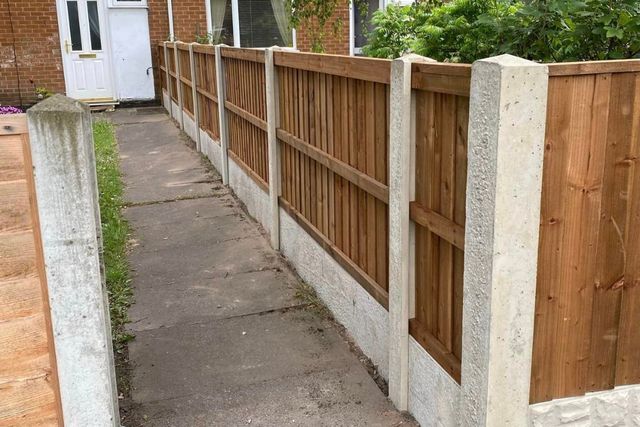A completed run of fencing on concrete posts and gravel boards beside a paved path in Top Valley