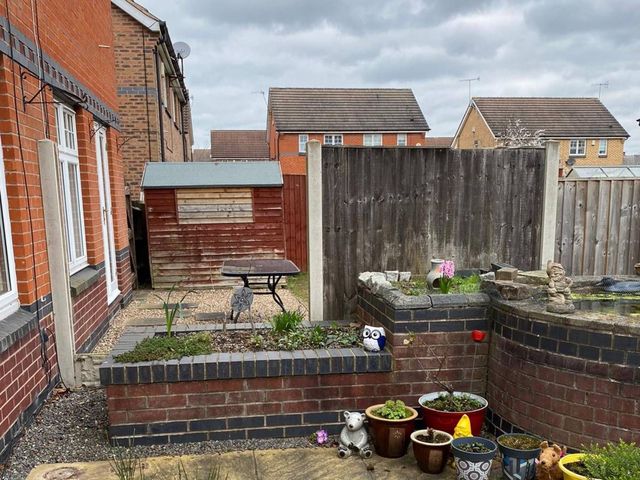 Weathered grey timber fence panels between concrete posts in an enclosed Basford garden before replacement