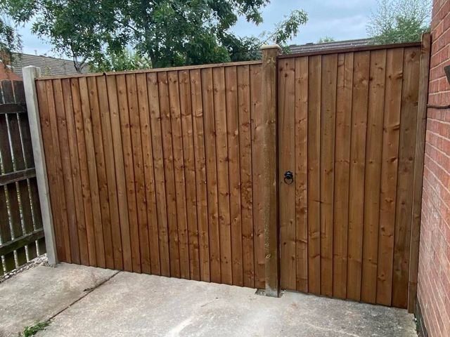 A tall closeboard fence with a matching gate closing off a side passage between properties in Lenton
